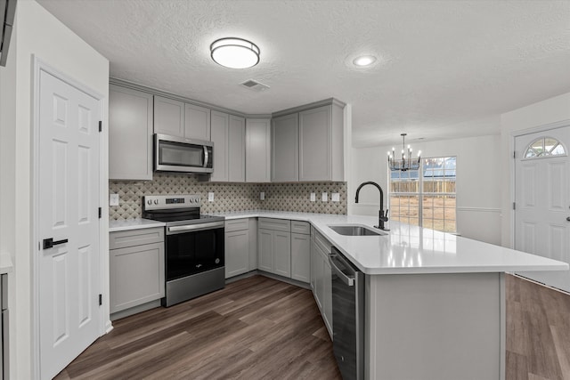 kitchen featuring sink, decorative light fixtures, kitchen peninsula, and appliances with stainless steel finishes