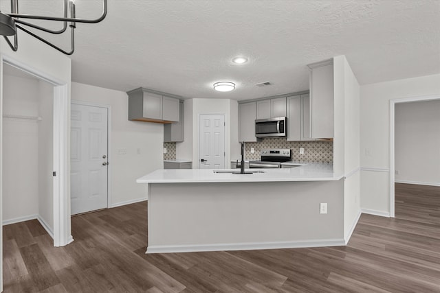 kitchen featuring gray cabinets, appliances with stainless steel finishes, tasteful backsplash, kitchen peninsula, and a textured ceiling