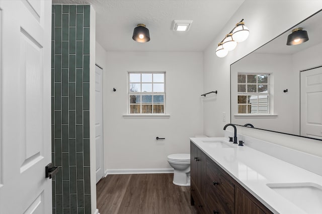 bathroom featuring vanity, wood-type flooring, a textured ceiling, and toilet