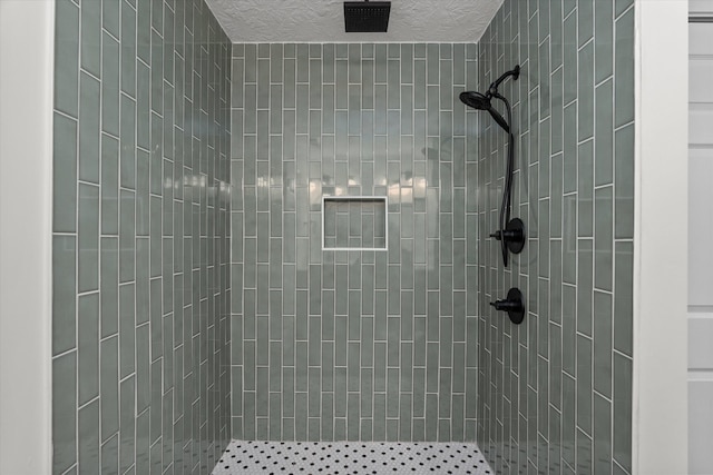 bathroom featuring a textured ceiling and a tile shower