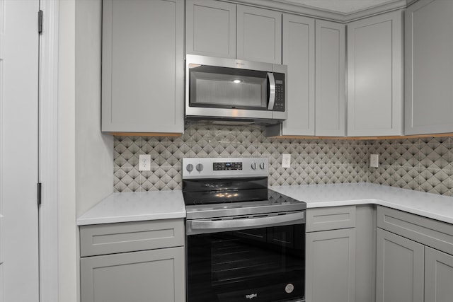 kitchen featuring tasteful backsplash, appliances with stainless steel finishes, light stone counters, and gray cabinetry