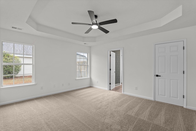 carpeted spare room featuring ceiling fan and a tray ceiling