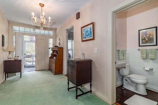 foyer entrance with carpet and a notable chandelier