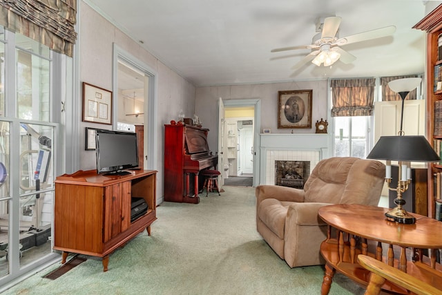 carpeted living room with ceiling fan and a tiled fireplace