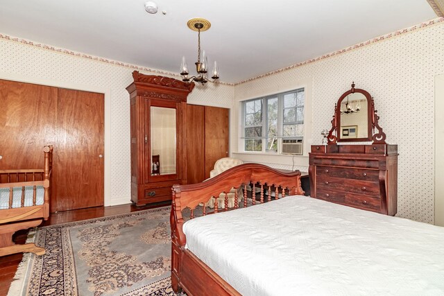 bedroom featuring cooling unit, dark wood-type flooring, and an inviting chandelier