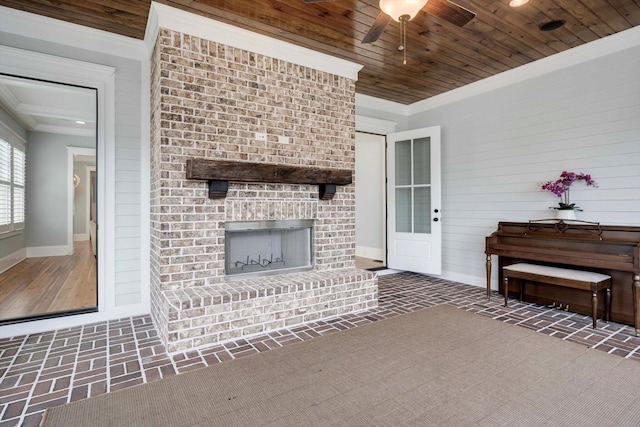 living area featuring a brick fireplace, brick patterned floor, baseboards, wood ceiling, and a ceiling fan