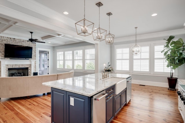 kitchen with light wood-type flooring, a sink, ceiling fan with notable chandelier, and blue cabinetry