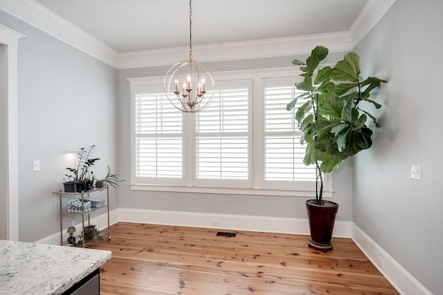 dining room with an inviting chandelier, ornamental molding, light wood-style flooring, and baseboards