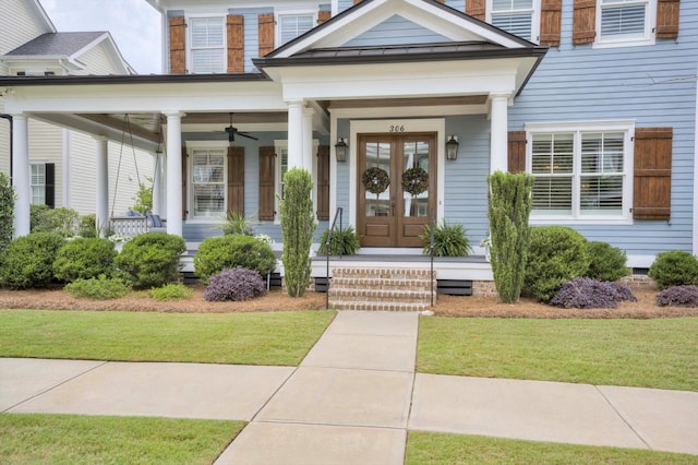 entrance to property with french doors, a ceiling fan, a yard, and a porch