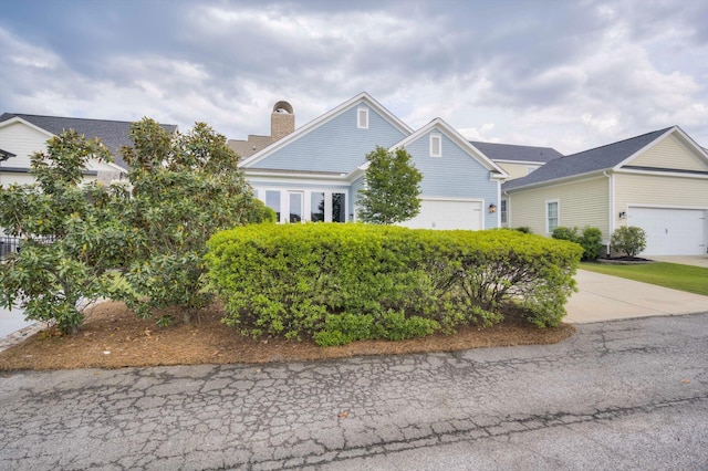 view of front of house featuring an attached garage, driveway, and a chimney