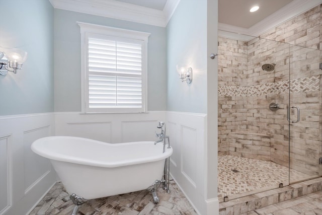 full bathroom featuring crown molding, a freestanding bath, wainscoting, a stall shower, and a decorative wall