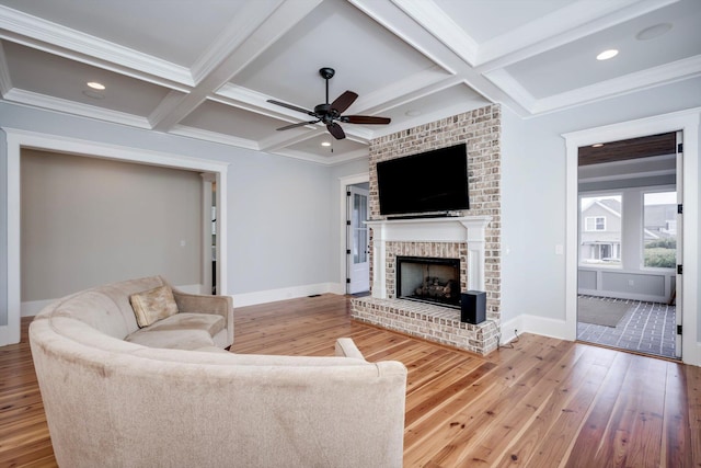 living area featuring ceiling fan, a fireplace, baseboards, coffered ceiling, and hardwood / wood-style floors