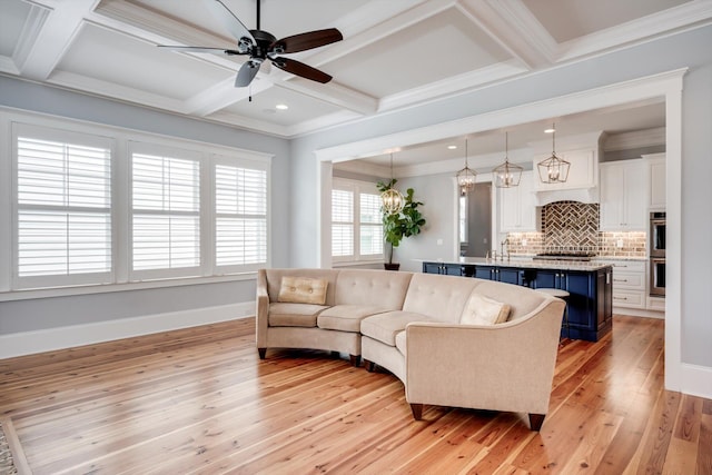 living room featuring light wood-type flooring, a ceiling fan, coffered ceiling, and baseboards