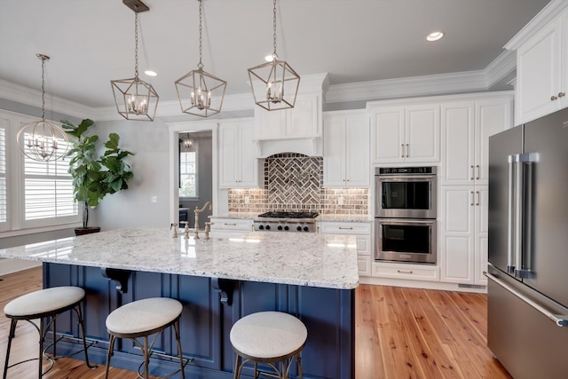 kitchen featuring white cabinets, stainless steel appliances, a chandelier, and light wood finished floors