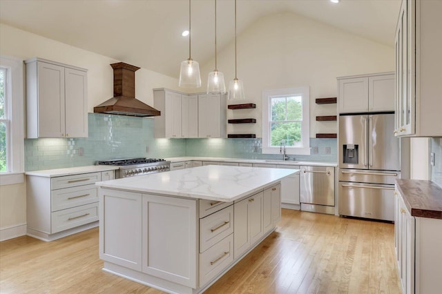 kitchen featuring sink, appliances with stainless steel finishes, high vaulted ceiling, a center island, and custom exhaust hood