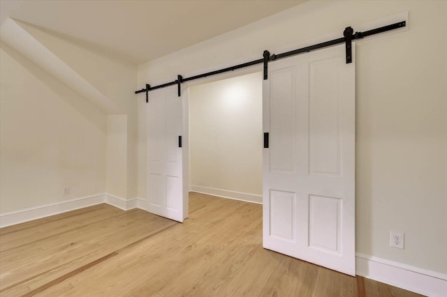 unfurnished room featuring a barn door and light hardwood / wood-style floors