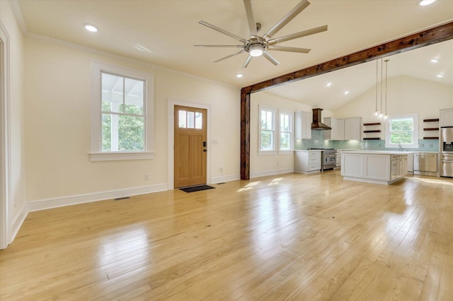 unfurnished living room with sink, crown molding, lofted ceiling with beams, light hardwood / wood-style flooring, and ceiling fan