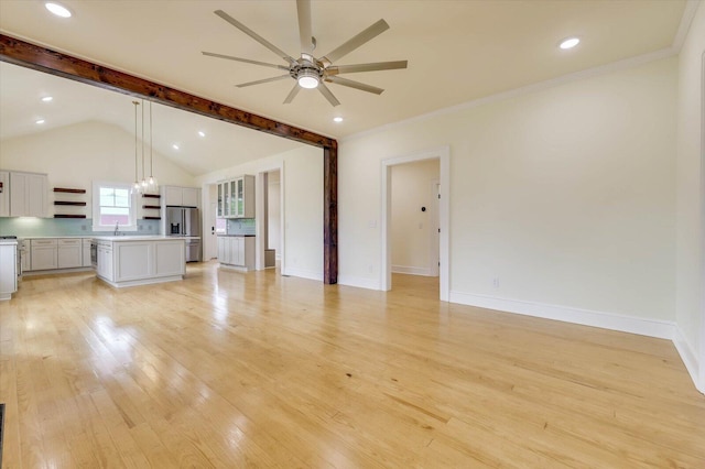 unfurnished living room with sink, crown molding, lofted ceiling with beams, ceiling fan, and light hardwood / wood-style floors