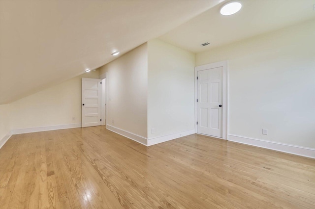 additional living space featuring lofted ceiling and light hardwood / wood-style flooring