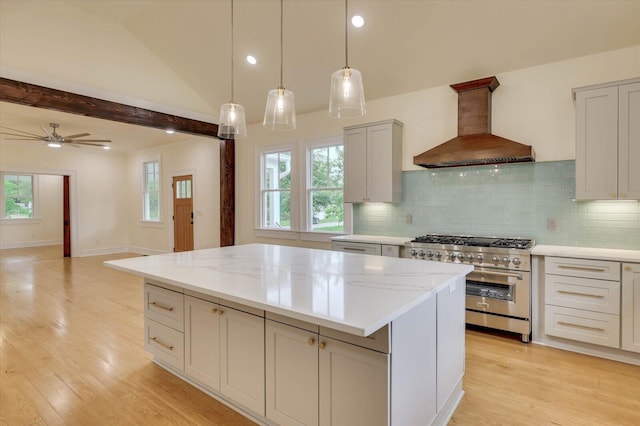 kitchen with stainless steel stove, hanging light fixtures, backsplash, a kitchen island, and custom exhaust hood