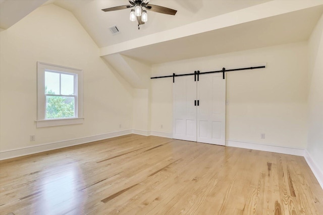 interior space featuring ceiling fan, lofted ceiling, a barn door, and hardwood / wood-style floors