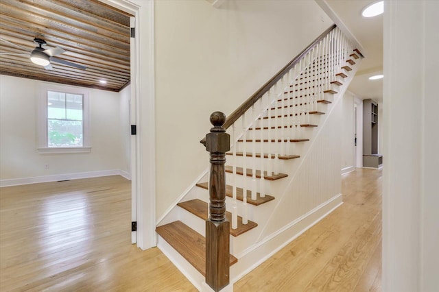 staircase with ceiling fan and hardwood / wood-style floors