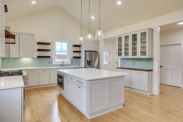 kitchen featuring sink, appliances with stainless steel finishes, hanging light fixtures, a center island, and white cabinets