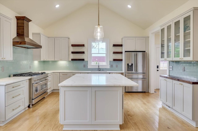 kitchen featuring a kitchen island, decorative light fixtures, high quality appliances, white cabinets, and wall chimney exhaust hood