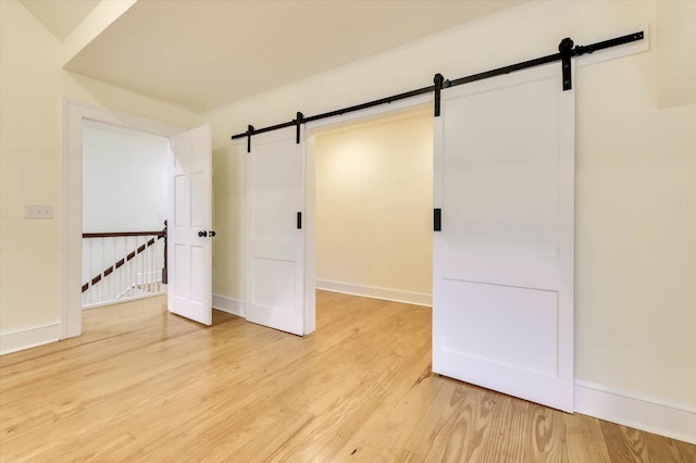 empty room with light hardwood / wood-style floors and a barn door