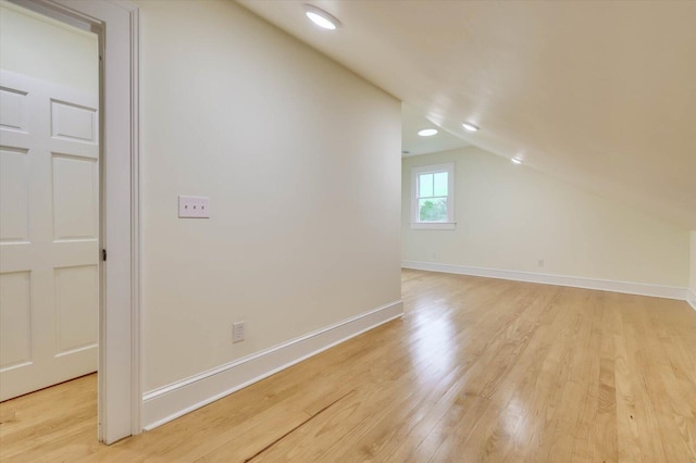 additional living space featuring vaulted ceiling and light hardwood / wood-style flooring