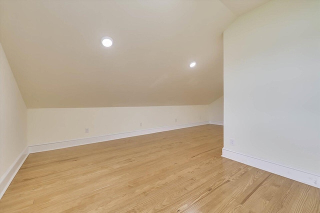 additional living space featuring vaulted ceiling and light hardwood / wood-style flooring