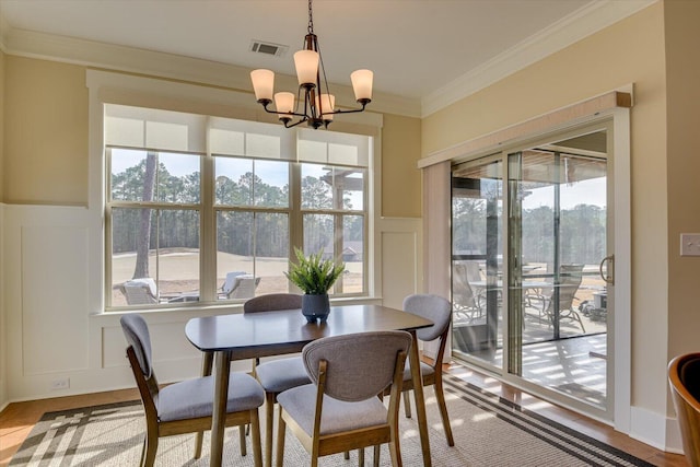 dining room with a notable chandelier, ornamental molding, and light wood-type flooring