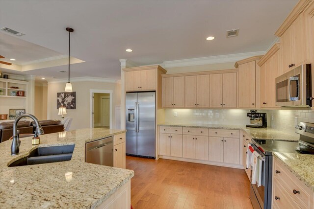 kitchen with light brown cabinetry, sink, light stone counters, appliances with stainless steel finishes, and pendant lighting