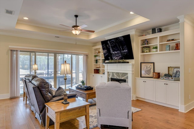 living room featuring plenty of natural light, a raised ceiling, and light wood-type flooring