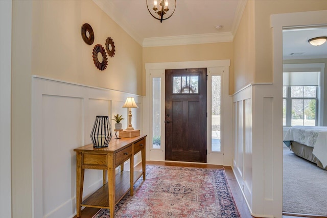 foyer entrance featuring crown molding, a notable chandelier, and hardwood / wood-style flooring