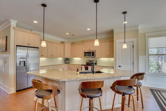 kitchen with appliances with stainless steel finishes, light brown cabinetry, sink, and a center island with sink