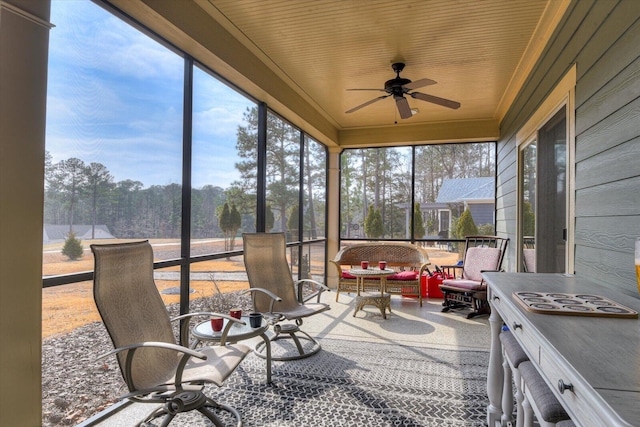 sunroom / solarium featuring a healthy amount of sunlight, wood ceiling, and ceiling fan