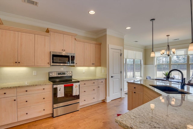 kitchen with hanging light fixtures, appliances with stainless steel finishes, sink, and light brown cabinetry