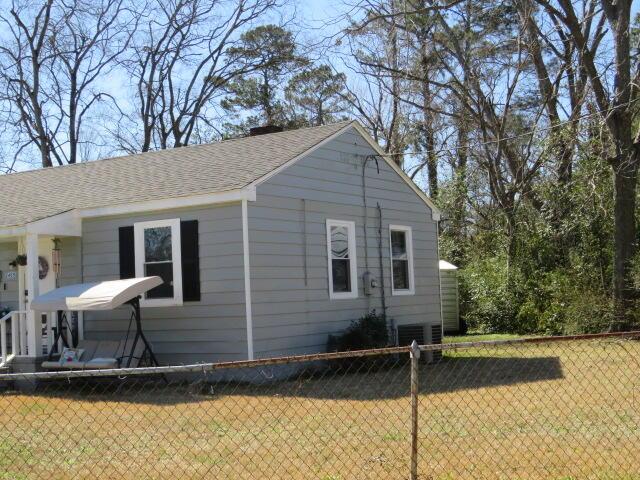 view of property exterior with roof with shingles, a yard, and fence