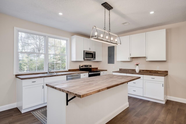 kitchen with pendant lighting, appliances with stainless steel finishes, wood counters, white cabinetry, and sink