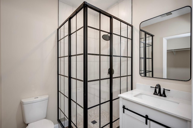 bathroom with toilet, a tile shower, and vanity