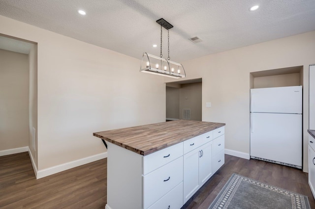 kitchen featuring white fridge, wooden counters, decorative light fixtures, a textured ceiling, and white cabinets