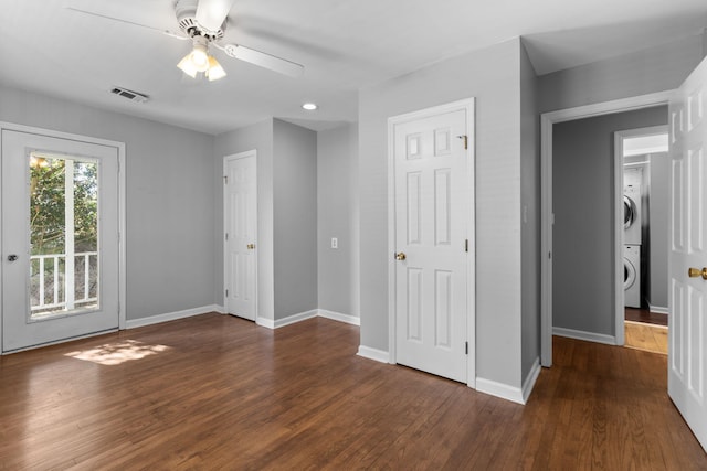 unfurnished bedroom with access to exterior, ceiling fan, stacked washer and dryer, and dark hardwood / wood-style floors