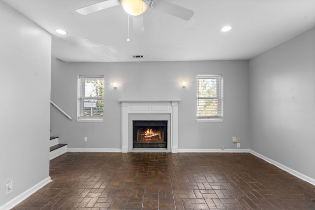 unfurnished living room featuring a wealth of natural light and ceiling fan