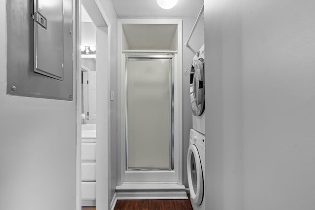 clothes washing area featuring dark hardwood / wood-style flooring, electric panel, and stacked washer / drying machine