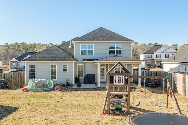 back of property with a playground, a yard, and a trampoline