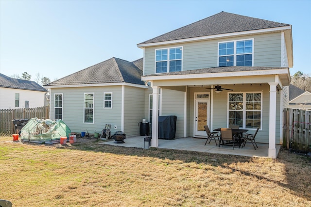 rear view of house featuring ceiling fan, a patio area, and a lawn