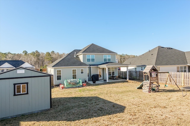 back of house with a playground, a yard, a patio area, and a storage shed