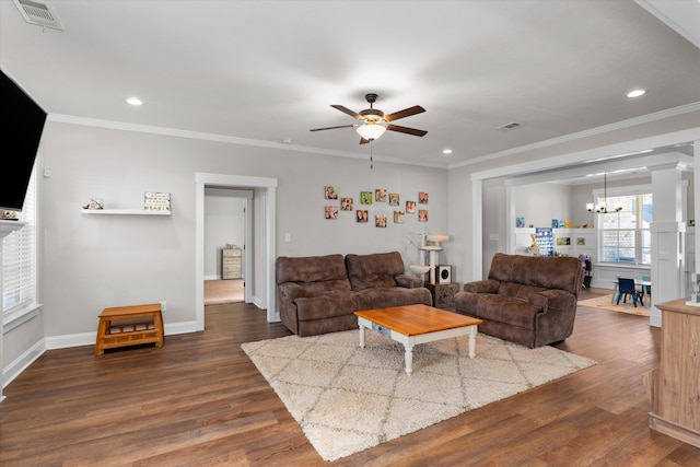 living room with ornamental molding, dark hardwood / wood-style flooring, and ceiling fan with notable chandelier