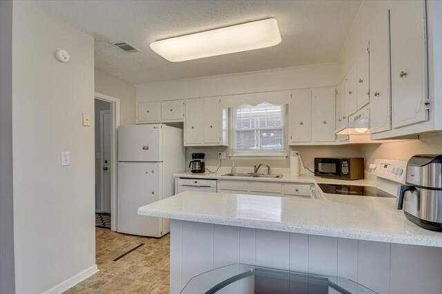 kitchen with kitchen peninsula, white refrigerator, white cabinets, and sink